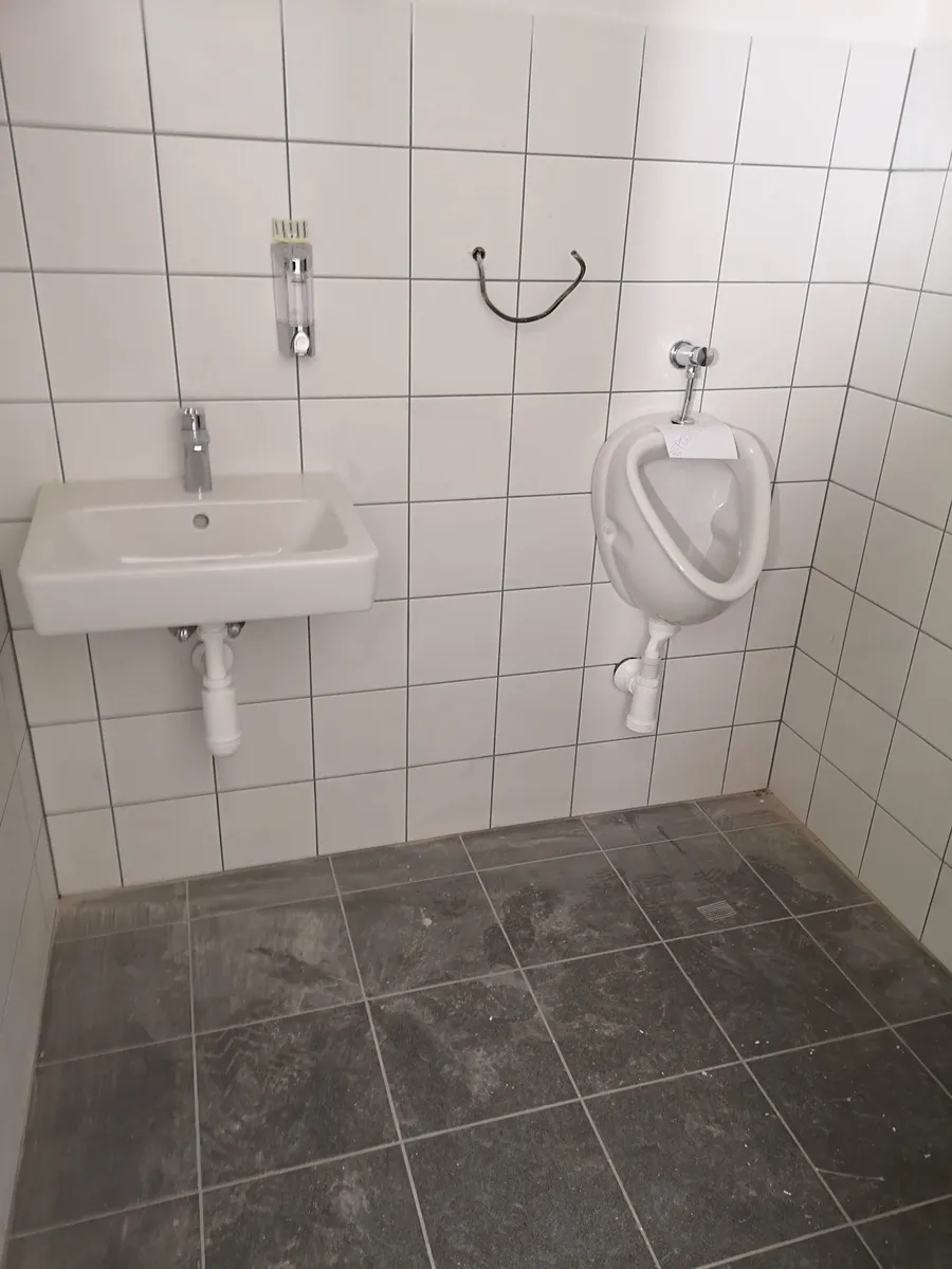 Osazené umyvadlo a pisoár v obložené koupelně