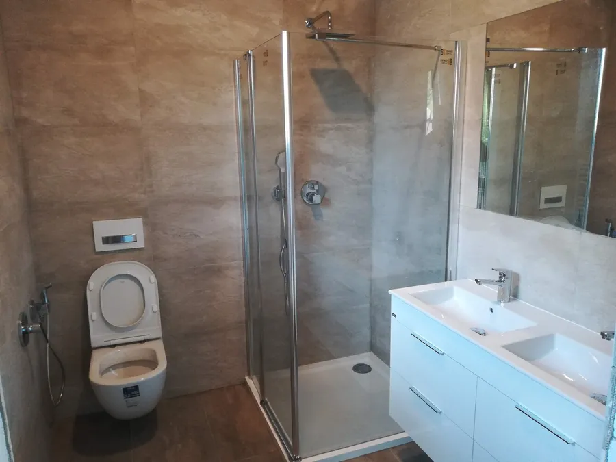 Osazený sprchový kout a umyvadlová skříňka v dokončené koupelně